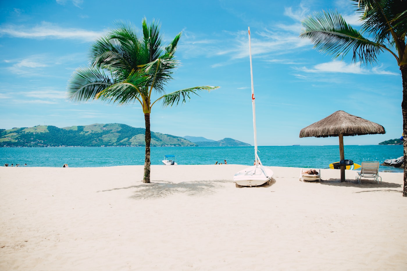 Palapa and sailboat on a calm turquoise beach